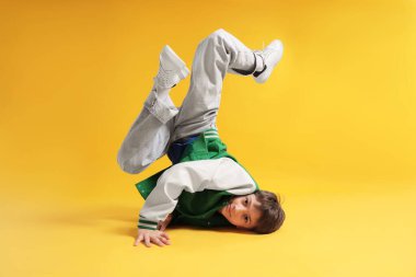 Şık giyinmiş çocuk turuncu arka planda dans ediyor.