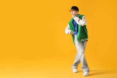 Şık giyinmiş çocuk turuncu arka planda dans ediyor, mesaj için yer var.