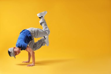 Şık giyinmiş çocuk turuncu arka planda dans ediyor, mesaj için yer var.