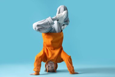 Şık giyinmiş çocuk açık mavi arka planda dans ediyor.