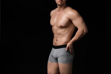 Siyah arka planda açık gri iç çamaşırlı genç adam, yakın plan.