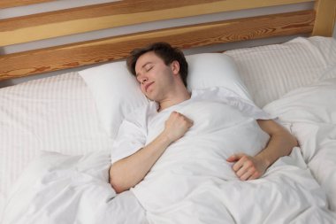 Genç adam yatağında uyuyor, yukarıda.