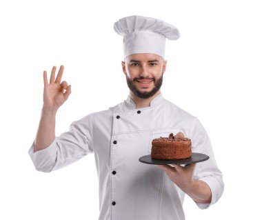 Üniformalı mutlu pastacı lezzetli çikolatalı pasta tutuyor ve beyaz arka planda güzel bir jest yapıyor.