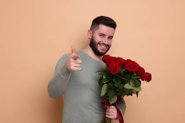 Bej arka planda kırmızı gül buketi olan mutlu adam.