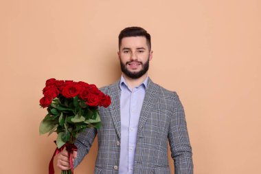 Bej arka planda kırmızı gül buketi olan mutlu adam.