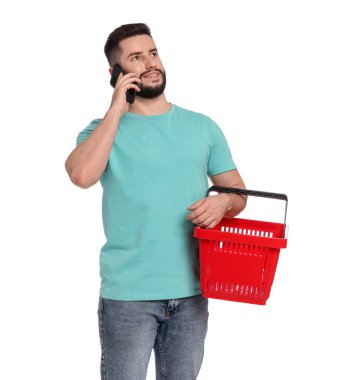 Boş alışveriş sepetli bir adam beyaz arka planda akıllı telefondan konuşuyor.