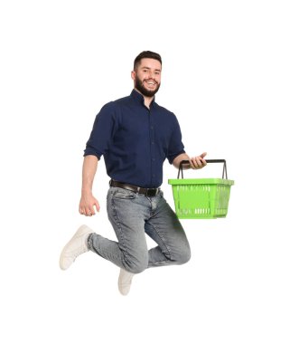 Beyaz arka planda atlayan boş alışveriş sepeti olan bir adam.