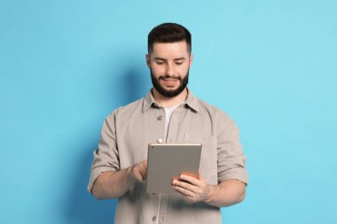 Açık mavi arkaplanda tablet kullanan adam