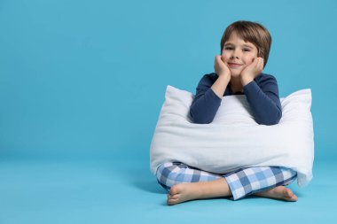 Açık mavi arka planda yastığı olan sevimli bir çocuk. Metin için boşluk