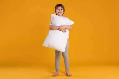 Turuncu arka planda yastığı olan tatlı bir çocuk.