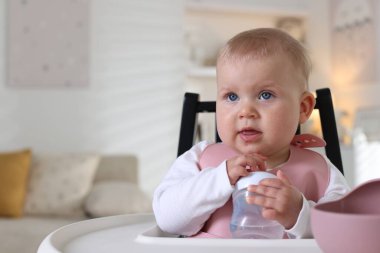 Evdeki yemek sandalyesinde biberonu olan şirin bir bebek. Metin için boşluk