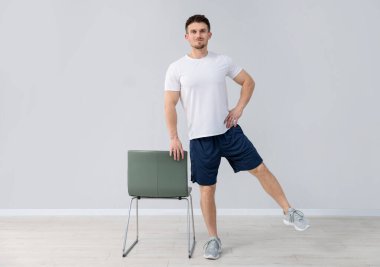 Evde sandalyeyle egzersiz yapan yakışıklı adam.