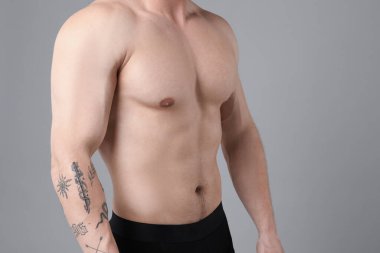 Açık gri arkaplan üzerindeki epilasyon işleminden sonra göğsü pürüzsüz genç adam, yakın plan