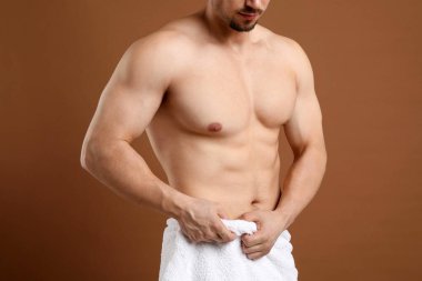 Kahverengi arka plandaki epilasyon işleminden sonra göğsü pürüzsüz genç adam, yakın plan.