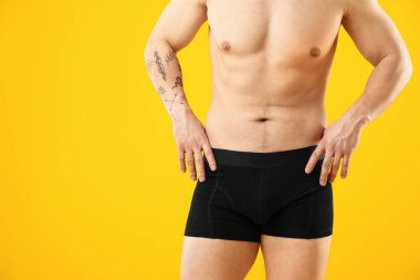 Turuncu arka planda siyah iç çamaşırlı genç adam, yakın plan. Metin için boşluk