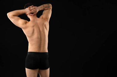 Siyah arka planda şık iç çamaşırlı genç bir adam. Metin için boşluk