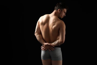 Siyah arka planda açık gri iç çamaşırlı genç adam.