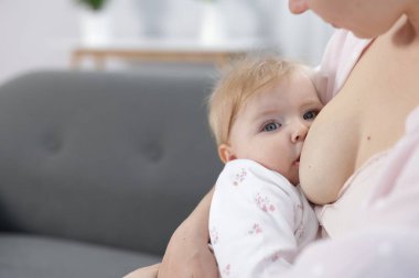 Anne küçük bebeğini evde emziriyor, yakın plan. Metin için boşluk