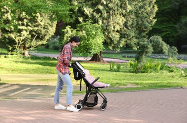 Anne bebeğiyle parkta bebek arabasında yürüyor. Metin için boşluk