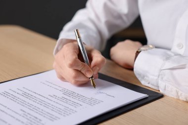 Ahşap masaya imza atan kadın, yakın plan.