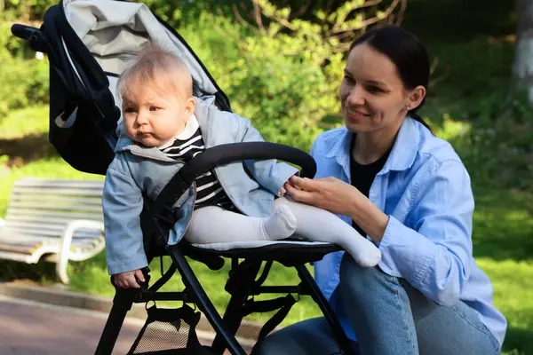 Parkta bebek arabasında sevimli bebeğiyle annesi