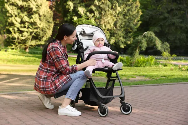 Parkta bebek arabasında sevimli bebeğiyle annesi
