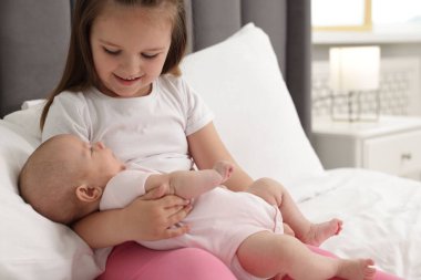 Sevimli kız ve küçük kız kardeşi evde yatakta, mesaj atmak için yer var.