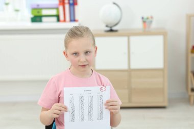 Okul derecesi. Kapalı alanda C harfi ve eksi sembolle cevap kağıdını tutan üzgün kız.