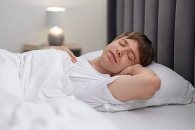Genç adam yatağında uyuyor.