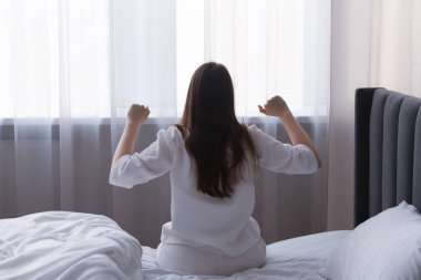 Evdeki yatakta gerinen kadın, arka manzara.