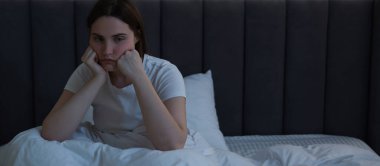 Yatakta uykusuzluk çeken, hayal kırıklığına uğramış genç bir kadın.