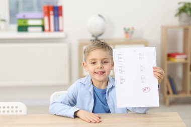Okul derecesi. A harfiyle cevap kağıdını tutan mutlu çocuk ve kapalı bir masada sembol.