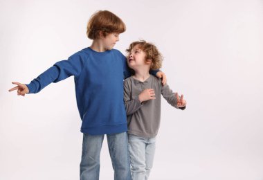 Beyaz arka planda V işaretleri gösteren sevimli küçük kardeşler.