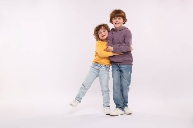 Beyaz arka planda kucaklaşan sevimli küçük kardeşler.