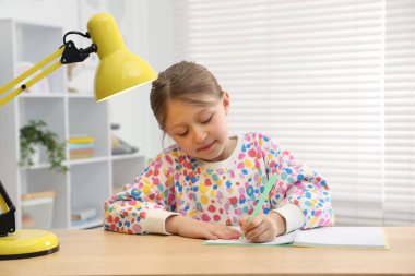 Küçük kız ev ödevlerini içeride yapıyor.