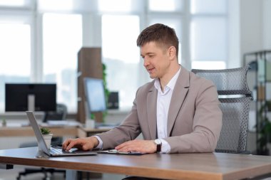 Ofiste masada dizüstü bilgisayarda çalışan adam