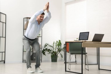 Ofiste masa başında egzersiz yapan yakışıklı bir adam.