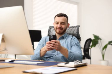 Ofiste çalışırken akıllı telefon kullanan bir adam.