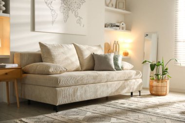 Oturma odasında yastıkları ve çiçekleri olan rahat bir kanepe.