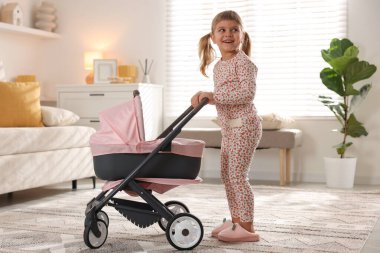 Evinde oyuncak bebek arabası olan sevimli küçük bir kız.