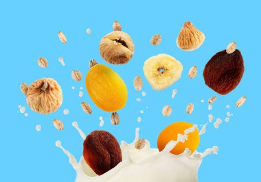 Süt sıçraması, yulaf ezmesi ve açık mavi arka planda kuru meyveler. Sağlıklı kahvaltı.