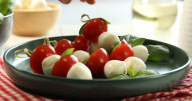 Bir kadın mozzarella peyniri, domates ve fesleğenle aperatif alıyor.