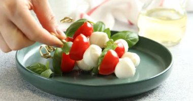 Kadın mozzarella peyniri, domates ve fesleğenle aperatif hazırlıyor.