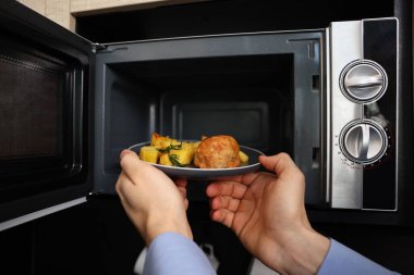 Yemek tabağını mikrodalgaya koyan adam, yakın plan.