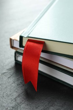 Kırmızı kurdele yer imi ve gri desenli masa üzerindeki renkli kitap, yakın plan.