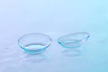 Kontakt lensler ve su damlaları mavi ayna yüzeyine, yakın plan.