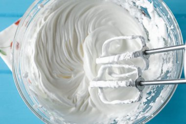 Açık mavi masada el çırpma kremi, üst görünüm.