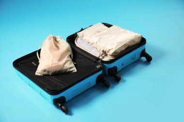 Açık mavi arkaplanda paketleme küpleri olan bavulu aç