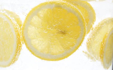 Beyaz arka planda limon dilimleri ile soda tazeleniyor, yakın plan.