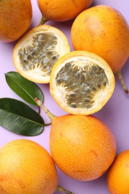 Olgun sarı çarkıfelek meyveleri ve yaprakları leylak arka planda, düz yatıyordu.